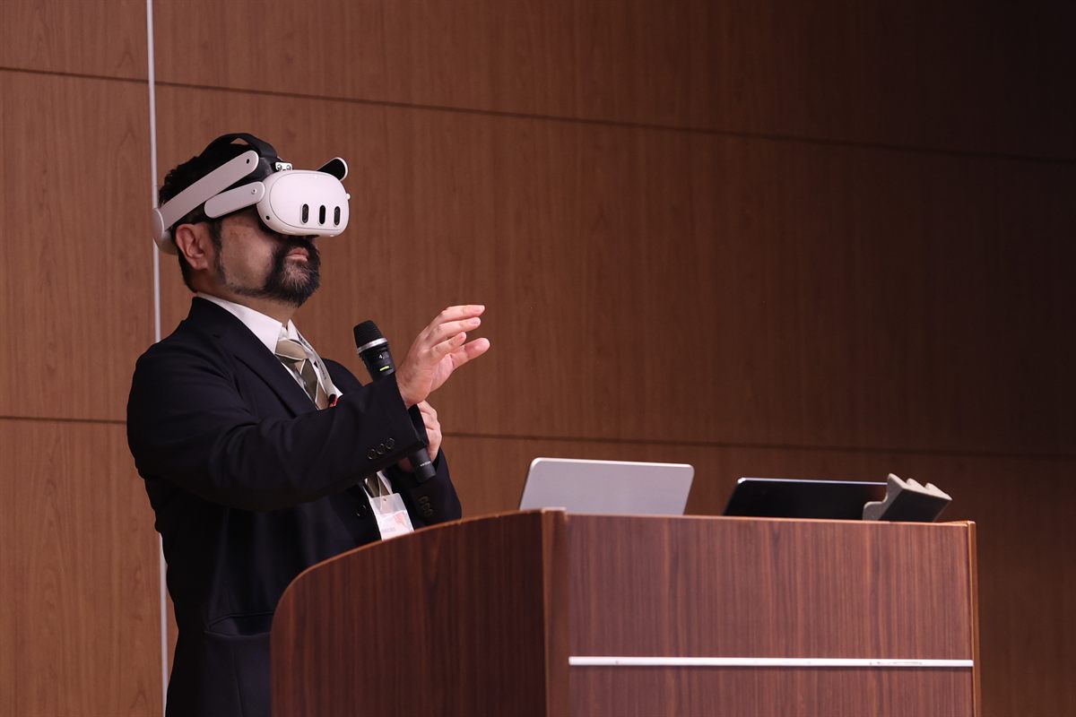 ヘッドマウントディスプレイを装着して実演する登壇者